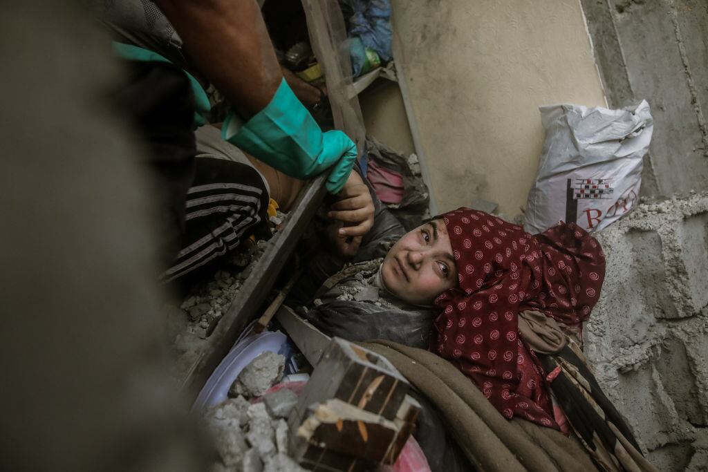 Un grupo de voluntarios palestinos intentan el rescate de una mujer atrapada en los escombros tras los bombardeos de Israel sobre la Franja de Gaza