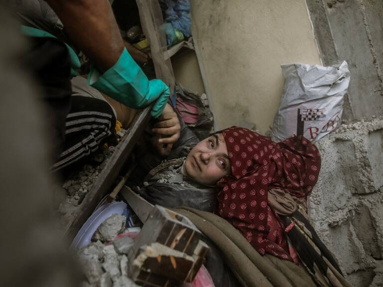 Un grupo de voluntarios palestinos intentan el rescate de una mujer atrapada en los escombros tras los bombardeos de Israel sobre la Franja de Gaza