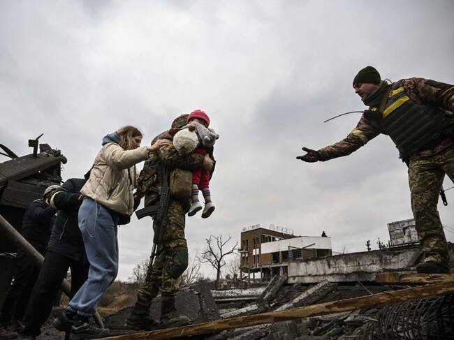 TOPSHOT – Un militar ucraniano carga a un niño mientras ayuda a las personas a cruzar un puente destruido mientras evacuan la ciudad de Irpin, al noroeste de Kiev, durante fuertes bombardeos y bombardeos el 5 de marzo de 2022, 10 días después de que Rusia lanzara una invasión militar en Ucrania. . (Foto de Aris Messinis / AFP) (Foto de ARIS MESSINIS/AFP vía Getty Images)