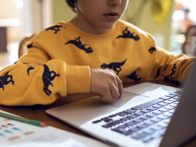 Close up of a young boy studying and doing homework using his laptop
