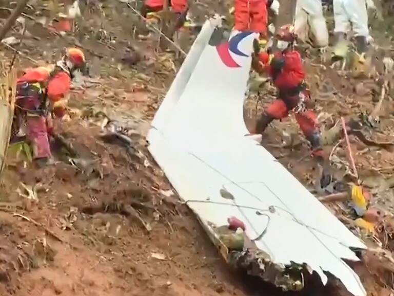 This screengrab taken on March 24, 2022 from video by state broadcaster China Central Television (CCTV) via AFPTV shows rescue teams with a piece of the fuselage as they continue their search at the site of where a China Eastern passenger jet crashed onto a mountainside near Wuzhou City in China's southern Guangxi region. - The cause of the disaster which killed 132 people has mystified aviation authorities who have scoured rugged terrain for clues, finding no survivors from what is almost certain to be China's deadliest plane crash in nearly 30 years. - China OUT (Photo by various sources / AFP) / China OUT (Photo by STR/AFPTV/AFP via Getty Images)