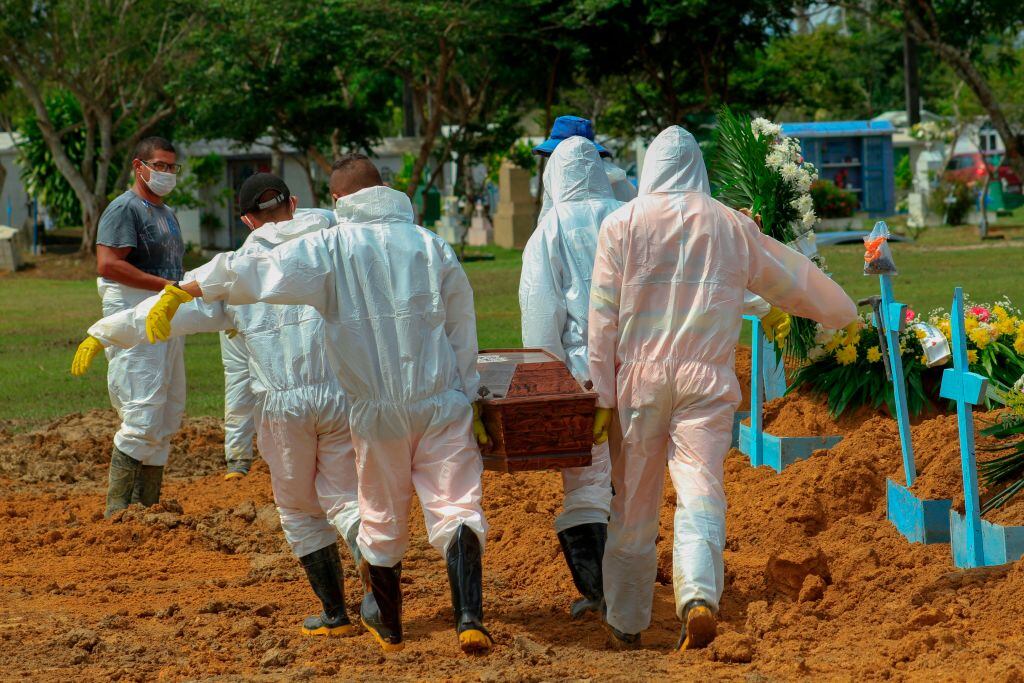 Trabajadores de un cementerio llevan a una víctima del Covid-19 en Brasil