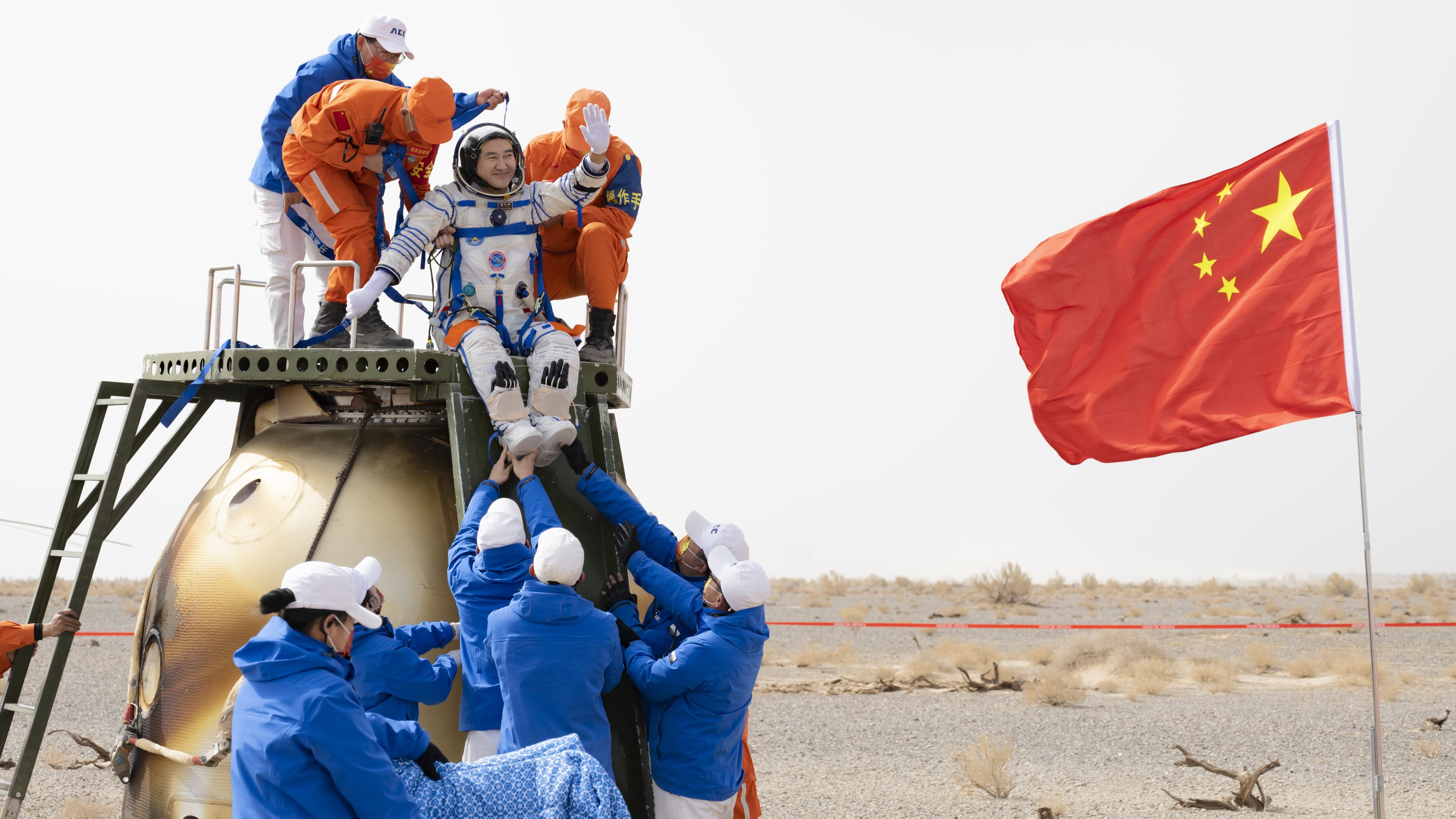 EJIN BANNER, CHINA - APRIL 16: Astronaut Zhai Zhigang waves as he is helped to disembark from the return capsule at the Dongfeng landing site on April 16, 2022 in Ejin Banner, Alxa League, Inner Mongolia Autonomous Region of China. The three crew members of China's Shenzhou XIII mission returned to Earth safely after completing six-month space mission. (Photo by VCG/VCG via Getty Images)