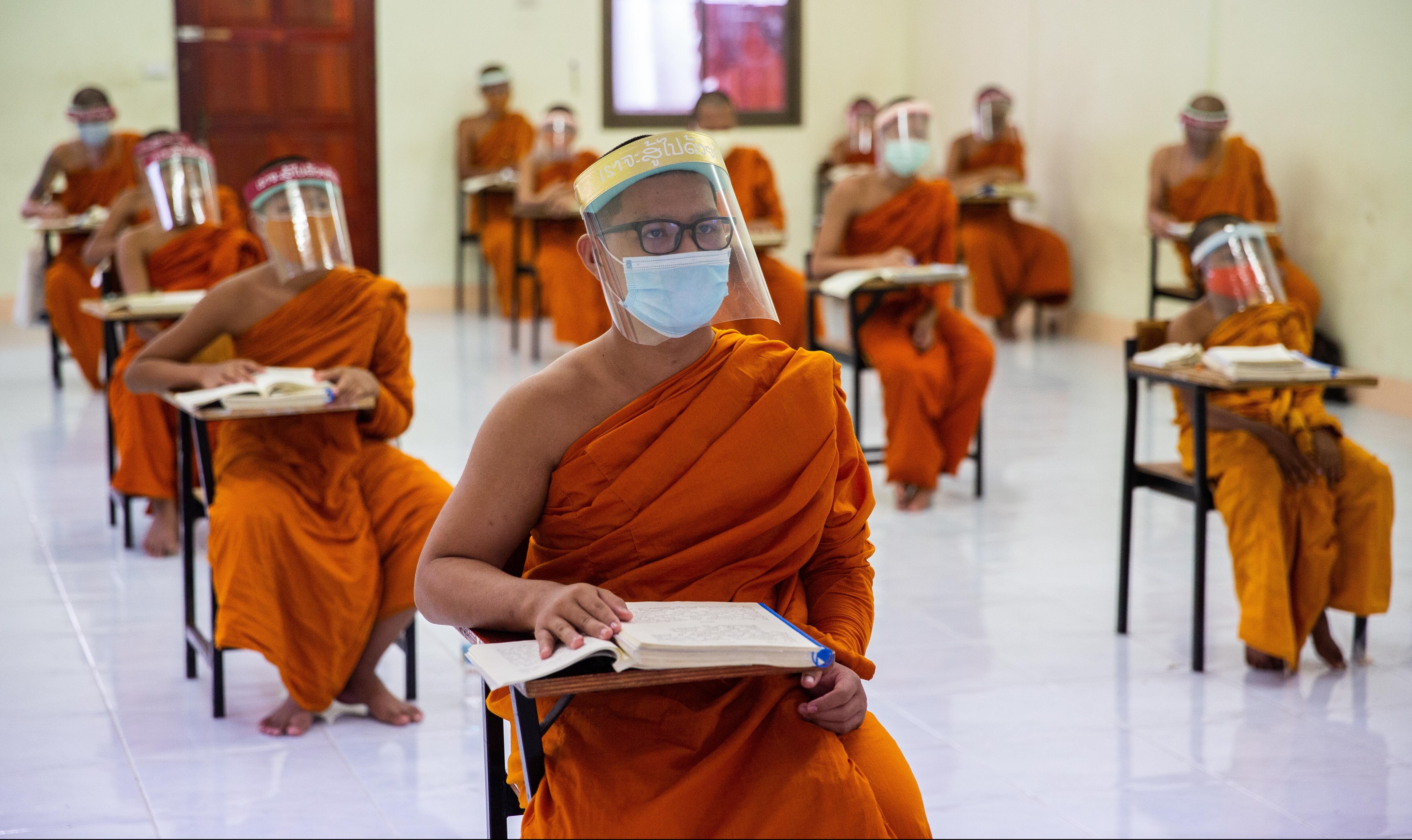 BANGKOK, THAILAND - APRIL 17: Thai Monks wear face maks and face shields to protect themselves from the coronavirus during their Pali language course at Wat Molilokkayaramon April 17, 2020 in Bangkok, Thailand. Though many Thai Monks in Bangkok left the city to wait out the coroavirus pandemic, Wat Molilokkayaram continues to house and teach over 200 monks. Social distancing measures and personal protective equipment has been given to each novice and monk to ensure their safety during their lessons and shared living conditions. Thailand is in a state of partial lockdown following the spread of Covid-19, with 2,700 confirmed cases of the virus. (Photo by Lauren DeCicca/Getty Images)