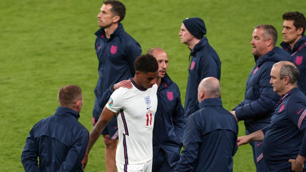 LONDON, ENGLAND - JULY 11:  Marcus Rashford of England surround by the England coaching staff after the penalty shootout during the UEFA Euro 2020 Championship Final between Italy and England at Wembley Stadium on July 11, 2021 in London, United Kingdom. (Photo by Marc Atkins/Getty Images)