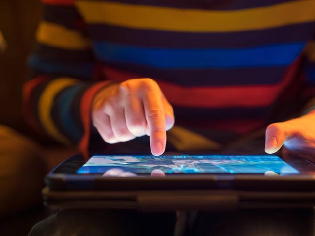 Close up of a young boy using a tablet computer, his finger hovering over it as he's about to touch the screen.