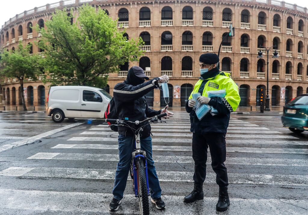 Un policía entrega mascarillas a las personas en la ciudad de Valencia