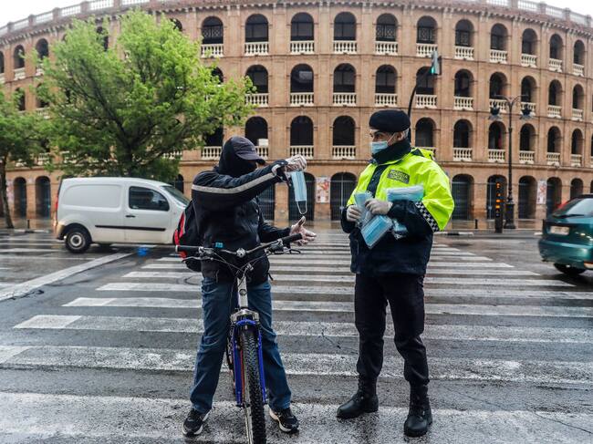 Un policía entrega mascarillas a las personas en la ciudad de Valencia