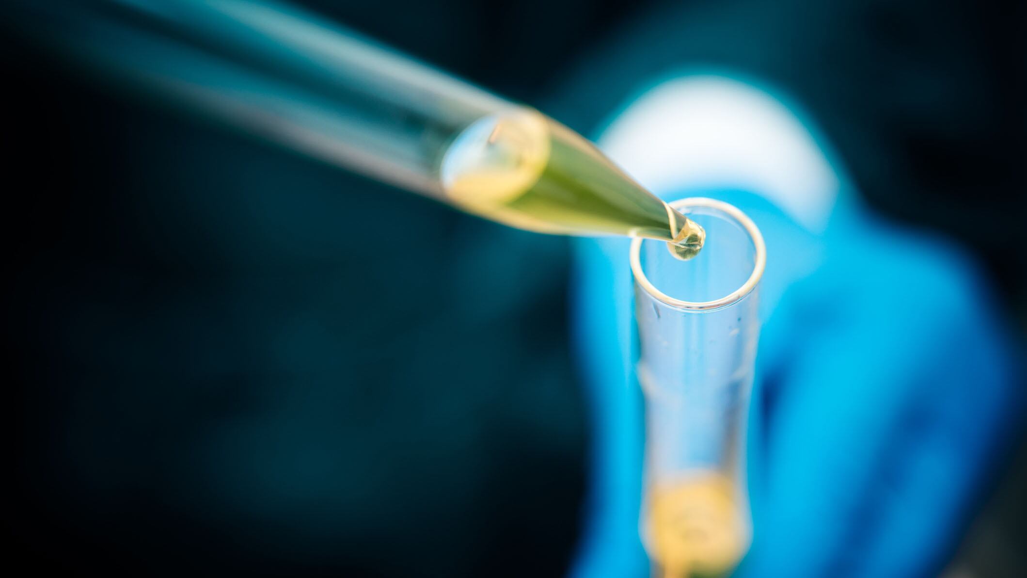 Laboratory technician using a pipette to fill a solution in a test tube, close-up.