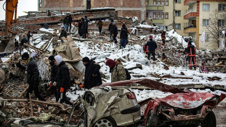 MALATYA, TURKIYE- FEBRUARY 7: People walk by as rescue workers search amongst the rubble after the earthquake struck on February 7, 2023 in Malatya, Türkiye. An earthquake with a magnitude of 7.8 occurred in the Pazarcık district of Kahramanmaraş ruins on February 6. (Photo by Hakan Akgun/ dia images)