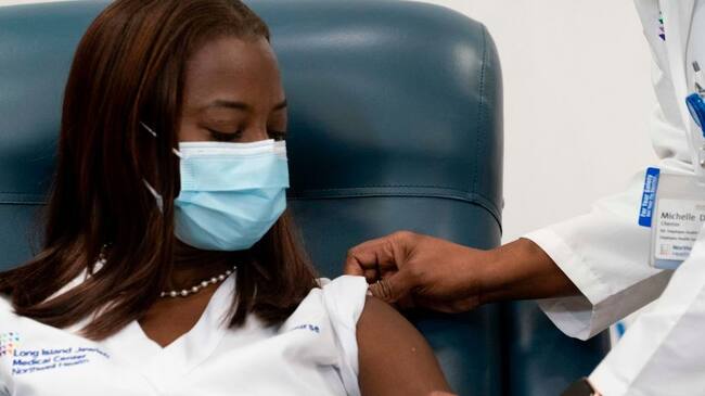 Dr. Michelle Chester(R), rolls up the sleeve of Sandra Lindsay, a nurse at Long Island Jewish Medical Center, before she is inoculated with the Pfizer-BioNTech Covid-19 vaccine at Long Island Jewish Medical Center, on December 14, 2020 in the Queens borough of New York. - The rollout of the Pfizer and BioNTech vaccine, the first to be approved by the Food and Drug Administration, ushers in the biggest vaccination effort in US history. More than 299,000 Americans have been killed by the virus, including over 35,000 residents of New York state. (Photo by Mark Lennihan / POOL / AFP) (Photo by MARK LENNIHAN/POOL/AFP via Getty Images)