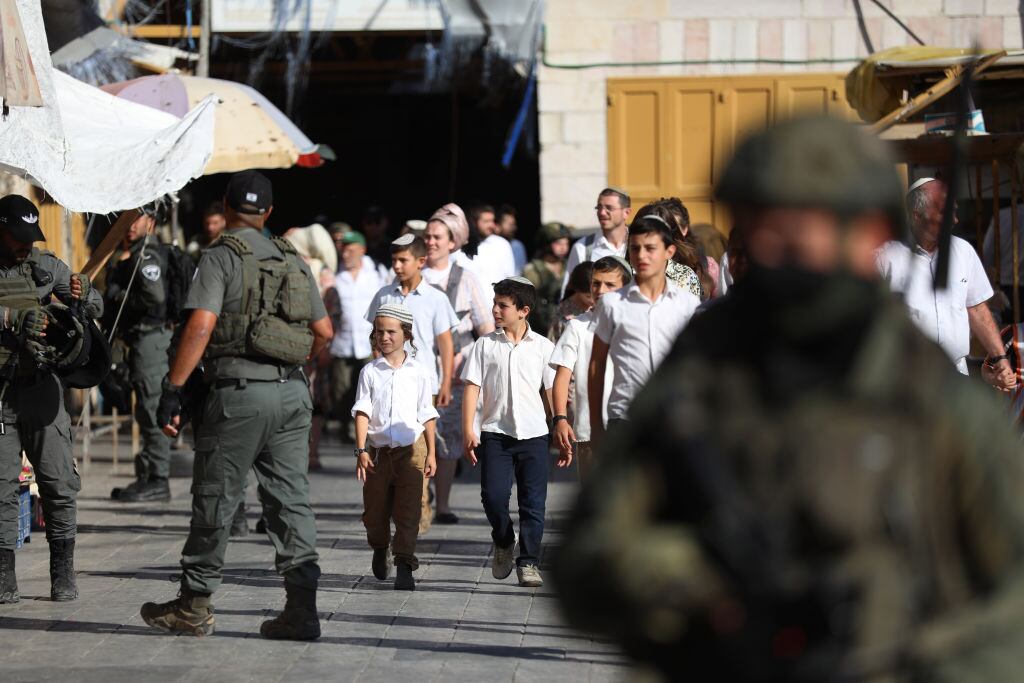 En el West Bank de Cisjordania unos militares israelíes custodian el avance de colonos judíos que caminan por territorios palestinos ocupados.