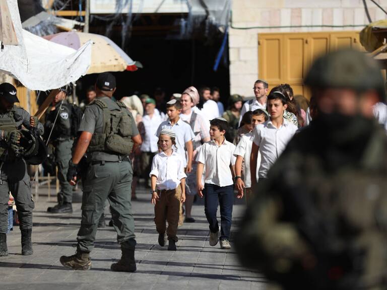En el West Bank de Cisjordania unos militares israelíes custodian el avance de colonos judíos que caminan por territorios palestinos ocupados.