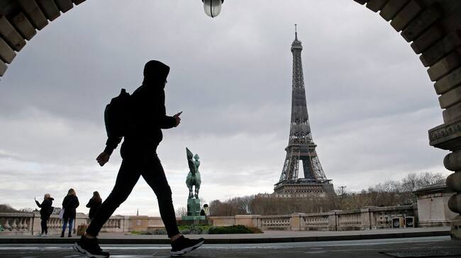 PARIS, FRANCE - MARCH 15: A man walks past the Eiffel Tower before the curfew, which begins at 6 p.m, during the coronavirus disease (COVID-19) outbreak on March 15, 2021 in Paris, France. The health situation is deteriorating in Ile-de-France and with very strong pressure on the hospitals, a lockdown of Ile-de-France on weekends is becoming more and more likely. This Monday, March 15, French President Emmanuel Macron spoke of "new decisions" which will be taken "in the coming days" . (Photo by Chesnot/Getty Images)