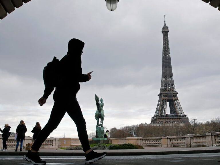PARIS, FRANCE - MARCH 15: A man walks past the Eiffel Tower before the curfew, which begins at 6 p.m, during the coronavirus disease (COVID-19) outbreak on March 15, 2021 in Paris, France. The health situation is deteriorating in Ile-de-France and with very strong pressure on the hospitals, a lockdown of Ile-de-France on weekends is becoming more and more likely. This Monday, March 15, French President Emmanuel Macron spoke of "new decisions" which will be taken "in the coming days" . (Photo by Chesnot/Getty Images)