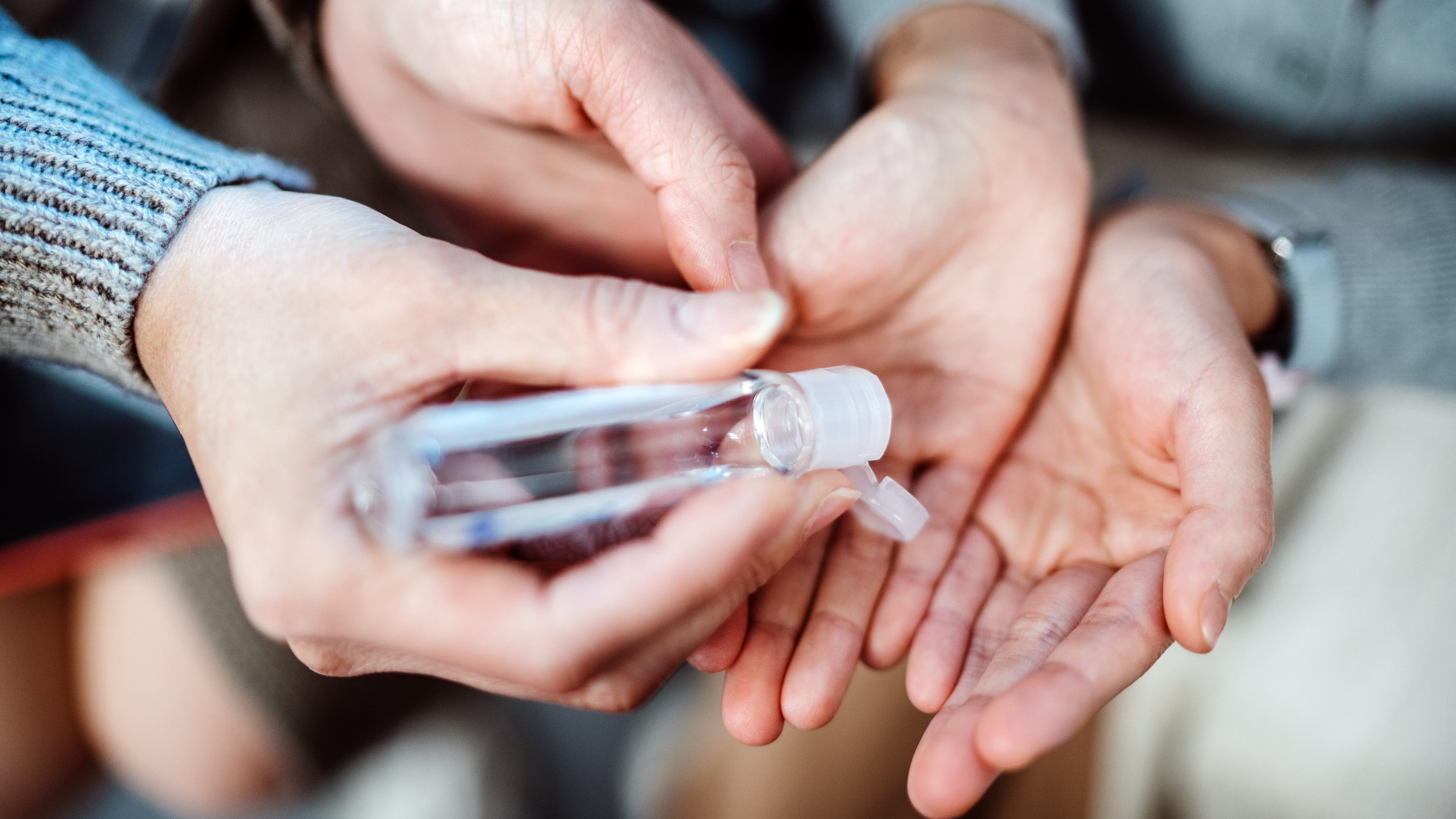 Mom squeezing hand sanitizer onto littler daughter’s hands
