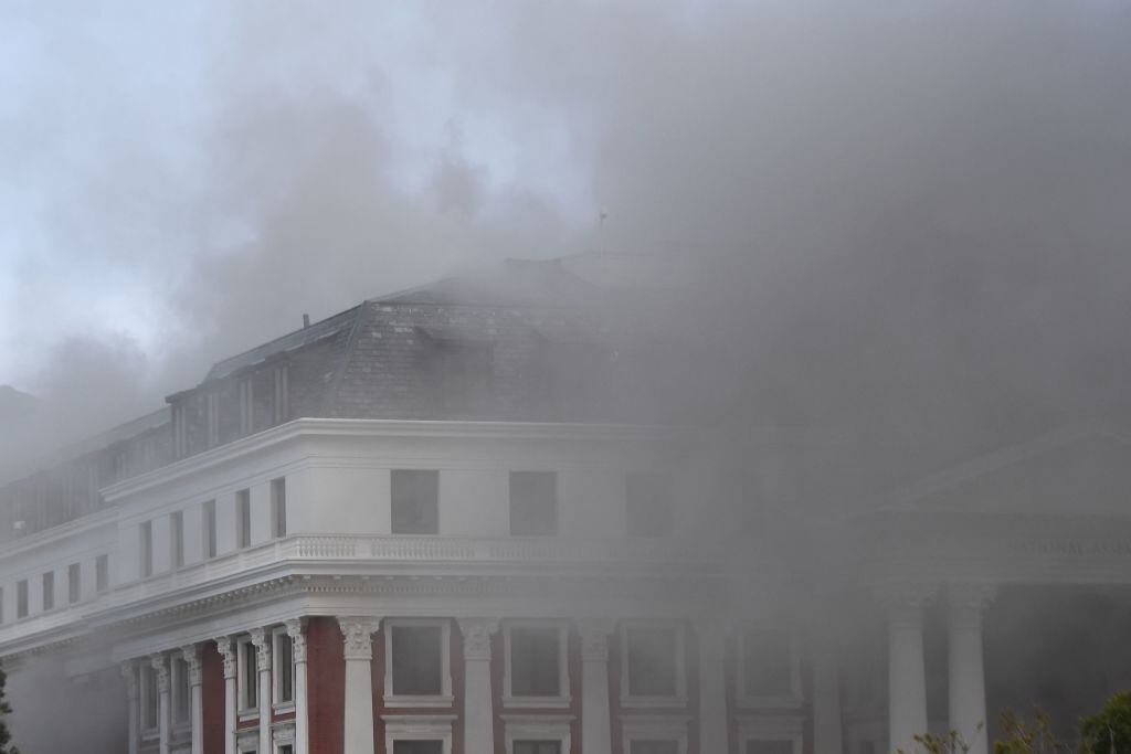 El humo cubre el cielo al salir de la sede del parlamento sudafricano