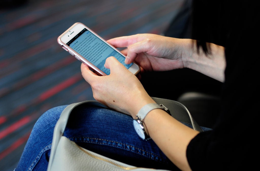 DALLAS, TX - SEPTEMBER 21, 2017: A woman uses her smartphone while waiting to board a plane at the Dallas/Fort Worth International Airport, located roughly halfway between Dallas and Fort Worth, Texas. (Photo by Robert Alexander/Getty Images)