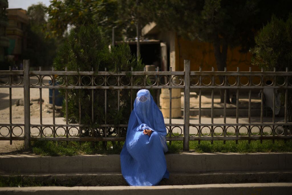 Mujer se mantiene sentada en la ciudad de Kabul con todo su cuerpo cubierto