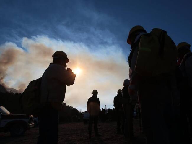 Voluntarios ven paso de helicóptero para combatir incendio forestal en México