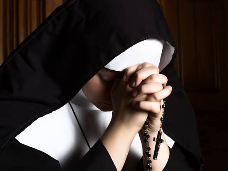 Fine art portrait of a novice nun in deep prayer with rosary