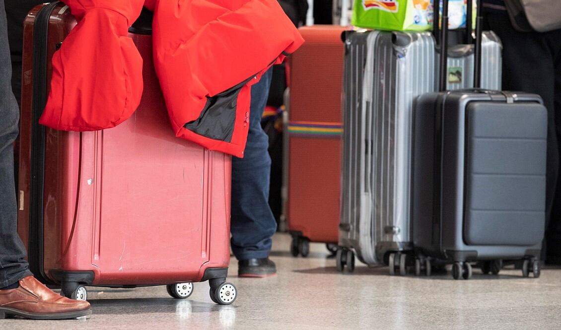 Un grupo de pasajeros llevan sus maletas en un aeropuerto