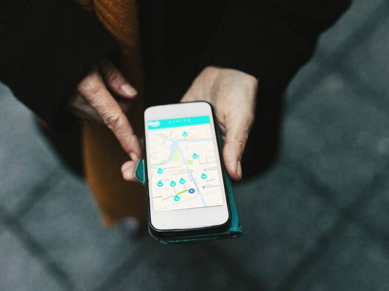 An aerial view of a woman using a car sharing app on her smartphone.