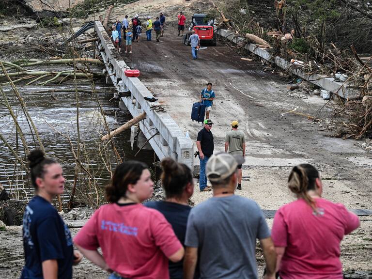 TOPSHOT - People look on as law enforcement and volunteers continue to search for missing people near Camp Mystic, the site of where at least 20 girls went missing after flash flooding in Hunt, Texas, on July 5, 2025. Rescuers were on Saturday searching for more than 20 girls missing from a riverside summer camp in the US state of Texas, after torrential rains caused devastating flooding that killed at least 27 people -- with more rain on the way. "So far, we've evacuated over 850 uninjured people, eight injured people and have recovered 27 deceased fatalities at this time. Of these 27, 18 are adults, nine are children," said Kerr Country Sheriff Larry Leitha on July 5. (Photo by RONALDO SCHEMIDT / AFP) (Photo by RONALDO SCHEMIDT/AFP via Getty Images)