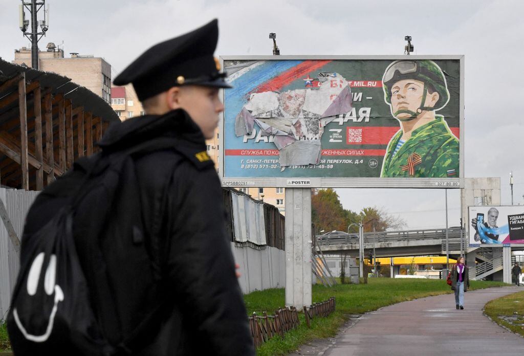 Cadete de Rusia ante un cartel de reclutamiento en San Petersburgo