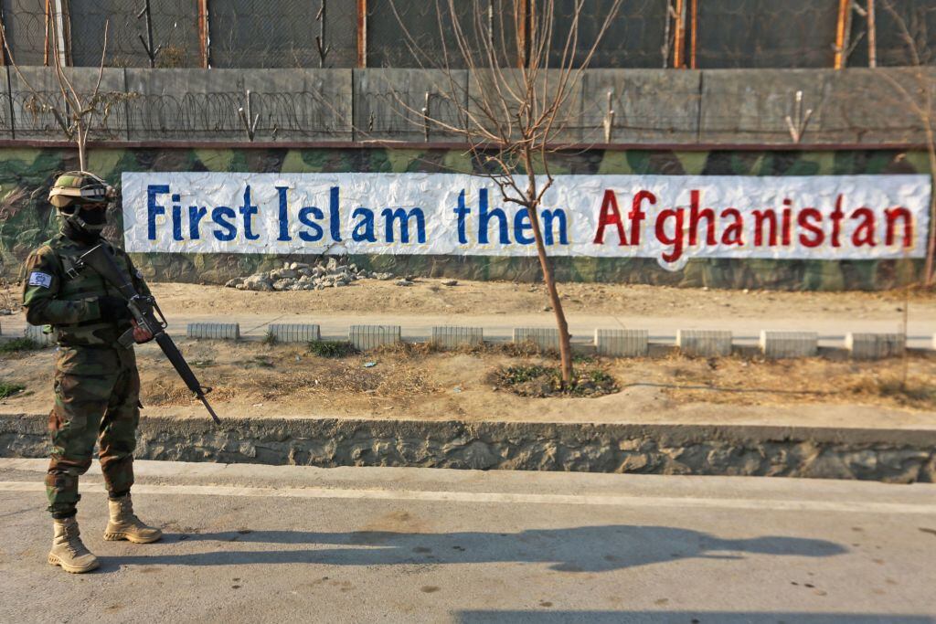Un militar talibán ante un cartel en Kabul que antepone el islam a Afganistán