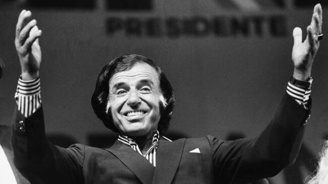 BUENOS AIRES, ARGENTINA - JULY 11: Argentine President Carlos Saul Menem greets with his arms raised during a Peronist political act in view of the legislative elections at Luna Park Stadium on July 11, 1991, in Buenos Aires, Argentina. (Photo by Ricardo Ceppi / Getty Images)