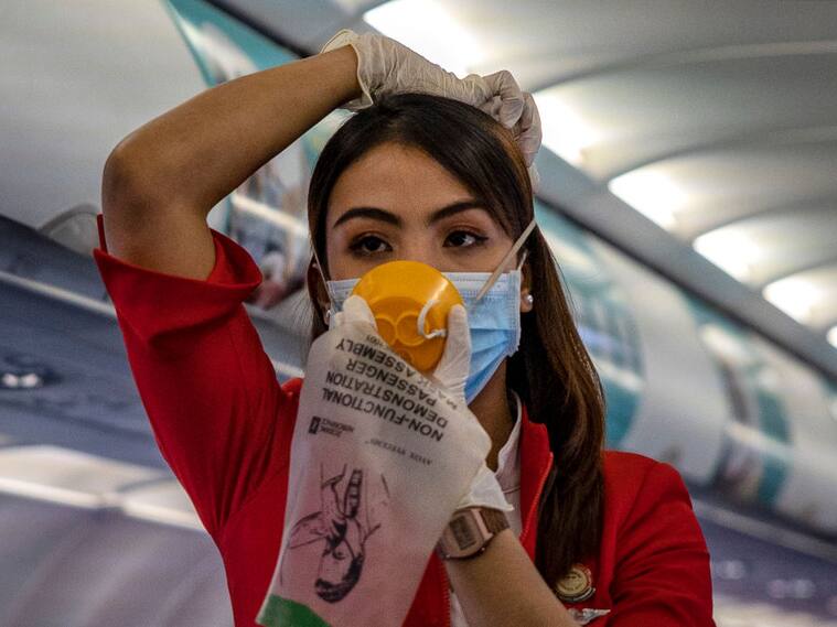 Una asistente de vuelo enseña medidas de protección utilizando una mascarilla por el coronavirus