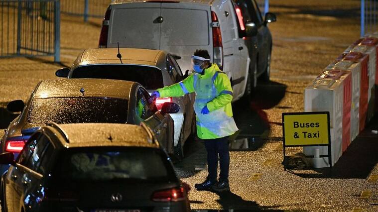 A Test and Trace worker wearing PPE talks to drivers at the Port of Dover, in Dover in Kent, south east England, on December 23, 2020, as the COVID-19 testing of drivers queueing to depart from the ferry terminal to Europe gets underway. - France and Britain reopened cross-Channel travel on Wednesday after a 48-hour ban to curb the spread of a new coronavirus variant but London has warned it could take days for thousands of trucks blocked around the port of Dover to get moving. (Photo by JUSTIN TALLIS / AFP) (Photo by JUSTIN TALLIS/AFP via Getty Images)