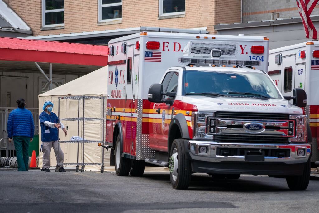 Trabajadores y una ambulancia en el frontis de un hospital de Nueva York