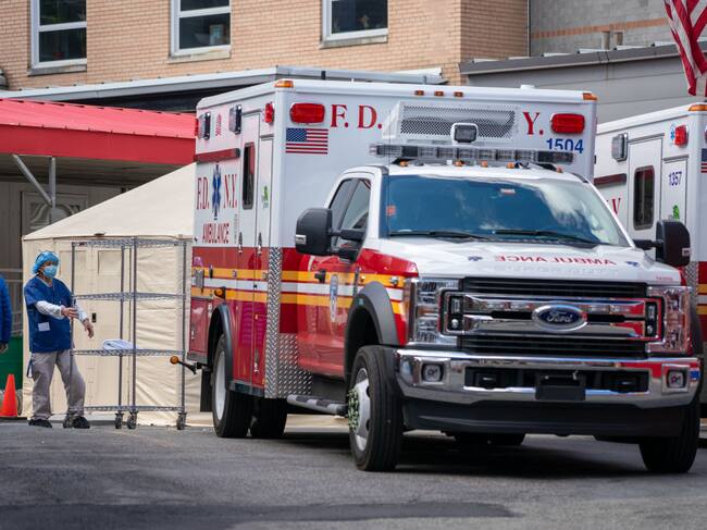 Trabajadores y una ambulancia en el frontis de un hospital de Nueva York