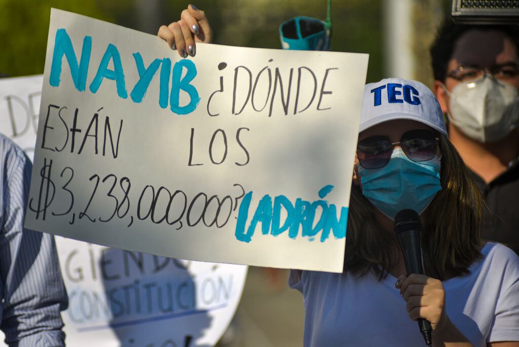 Una mujer con un cartel que acusa corrupción en el gobierno de Nayib Bukele