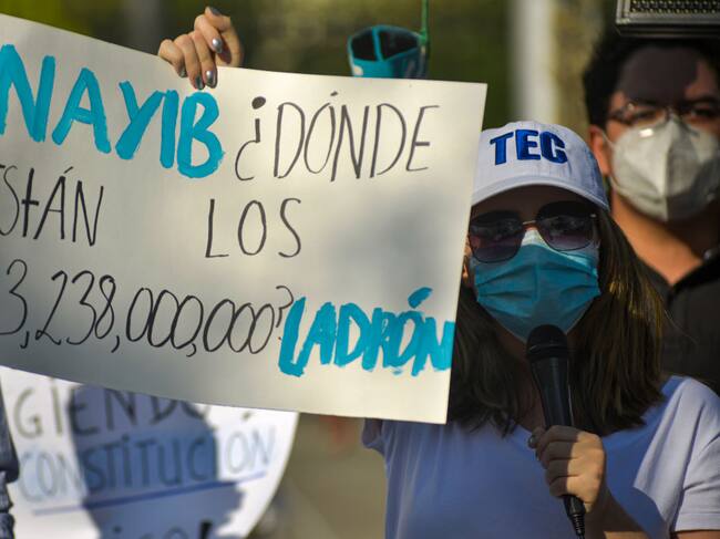Una mujer con un cartel que acusa corrupción en el gobierno de Nayib Bukele