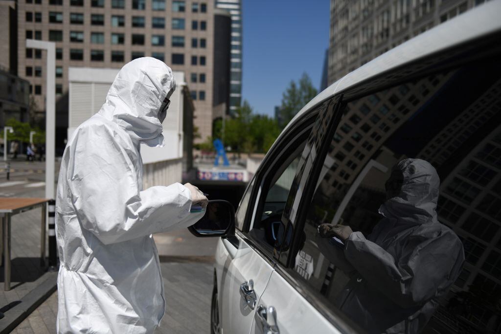 El trabajador de un estacionamientos utiliza un traje de protección en Pekín
