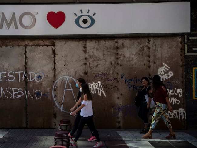 Una mujer camina por la ciudad de Santiago utilizando una máscara por el Covid-19