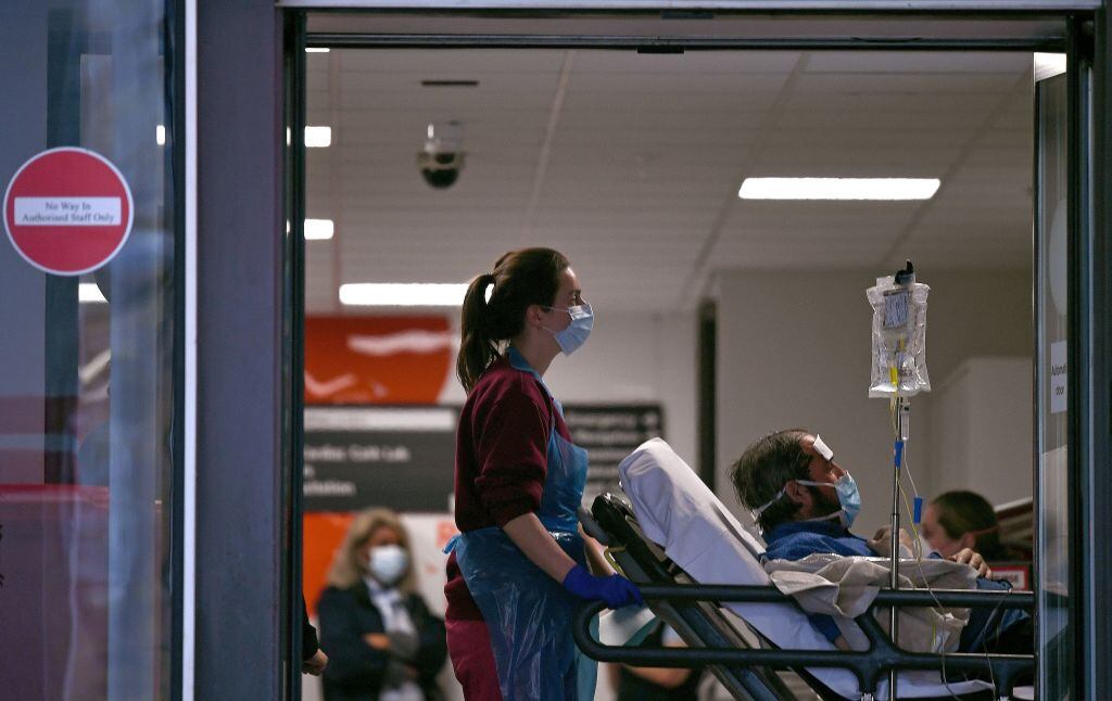 Una asistente médica conduce a un paciente en un hospital público de Inglaterra