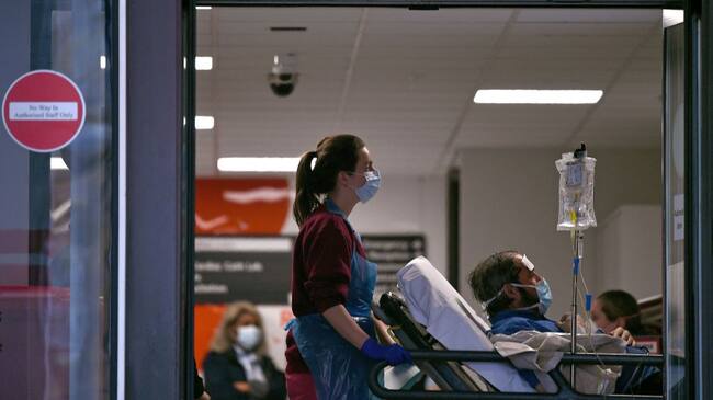 Una asistente médica conduce a un paciente en un hospital público de Inglaterra