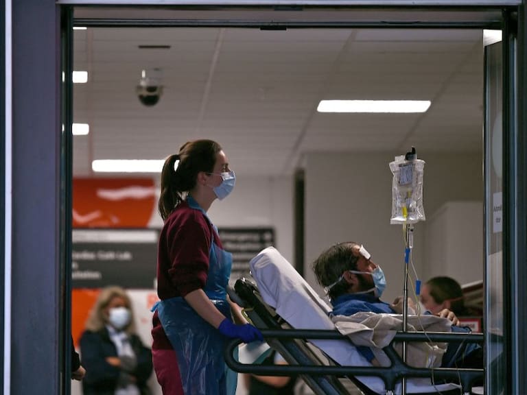 Una asistente médica conduce a un paciente en un hospital público de Inglaterra