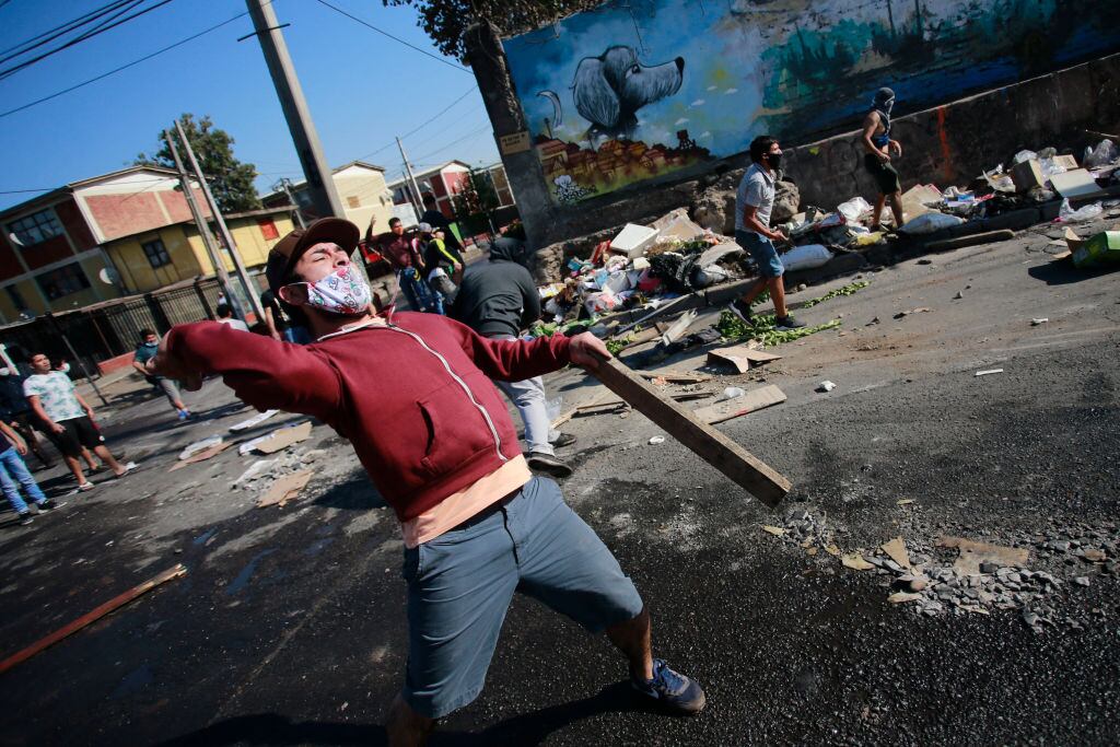 Demonstrators clash with riot police during a protest against Chilean President Sebastian Pinera's government amid the COVID-19 pandemic, in Santiago, on May 18, 2020. - Villagers in the populous commune of El Bosque, in southern Santiago, clashed with the police after protesting the lack of food and work as a result of the crisis caused by the coronavirus, which keeps the Chilean capital in total quarantine. (Photo by Pablo Rojas / AFP) (Photo by PABLO ROJAS/AFP via Getty Images)