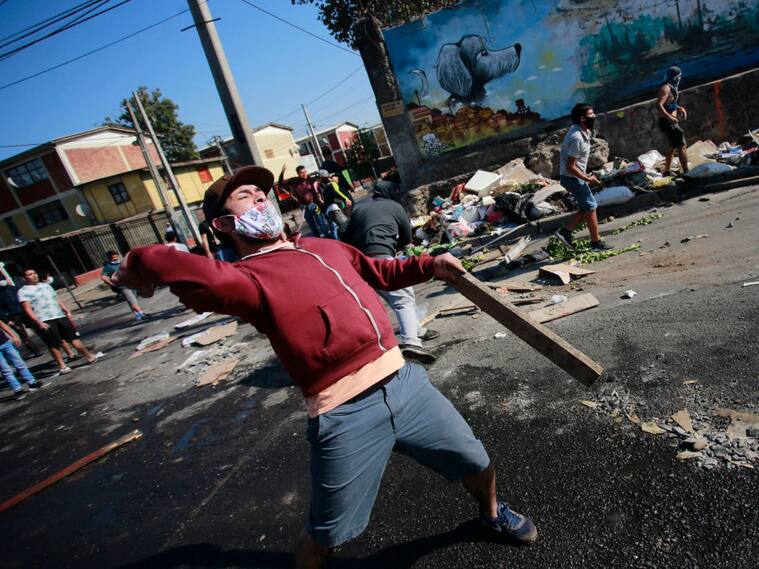 Demonstrators clash with riot police during a protest against Chilean President Sebastian Pinera's government amid the COVID-19 pandemic, in Santiago, on May 18, 2020. - Villagers in the populous commune of El Bosque, in southern Santiago, clashed with the police after protesting the lack of food and work as a result of the crisis caused by the coronavirus, which keeps the Chilean capital in total quarantine. (Photo by Pablo Rojas / AFP) (Photo by PABLO ROJAS/AFP via Getty Images)