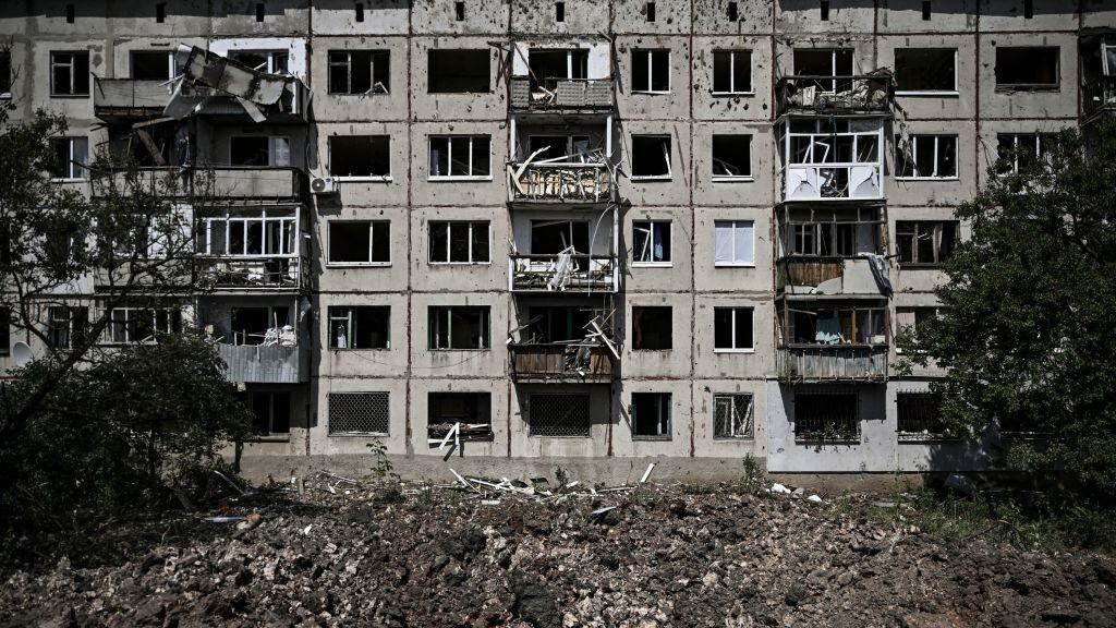 A picture shows a crater in front of a damaged apartment building after a missile strike in the city of Soledar, in the eastern Ukrainian region of Donbas on June 4, 2022. - Russian artillery is slamming Ukraine's eastern Donbas region with fierce fighting over the city of Severodonetsk, but the local governor says there was some progress in pushing back invading forces. (Photo by ARIS MESSINIS / AFP) (Photo by ARIS MESSINIS/AFP via Getty Images)