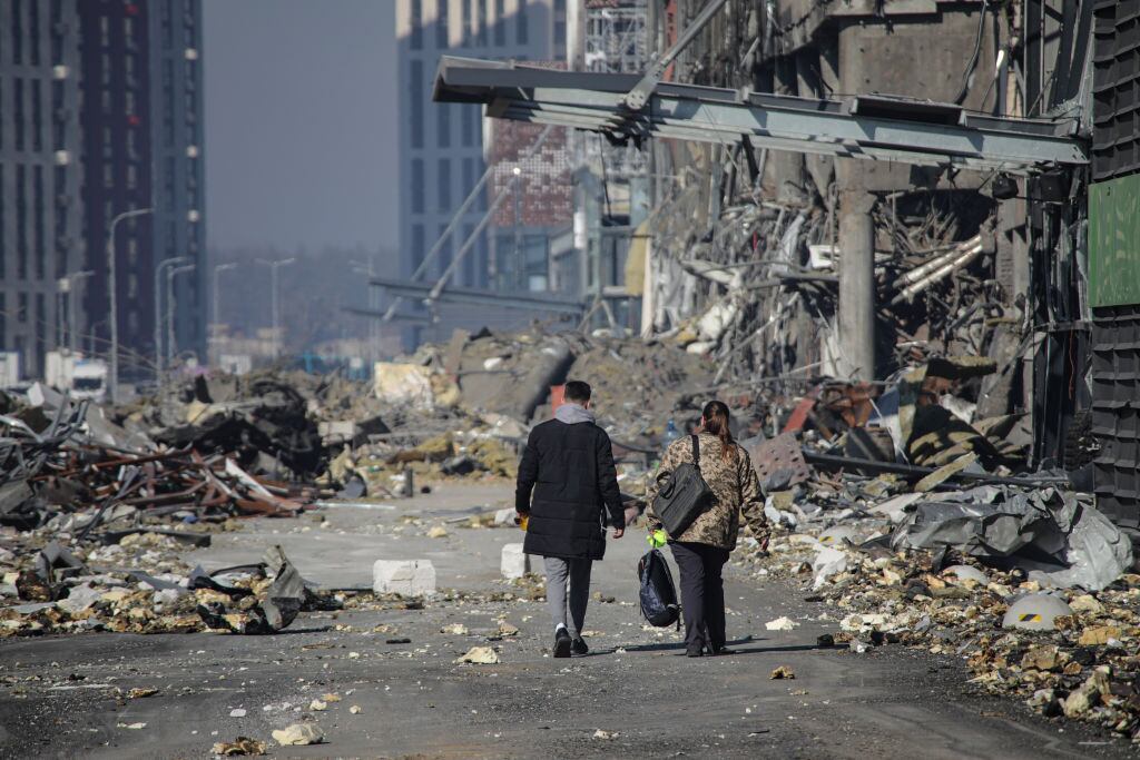 Personas caminan entre los escombros que generan los bombardeos en Kiev