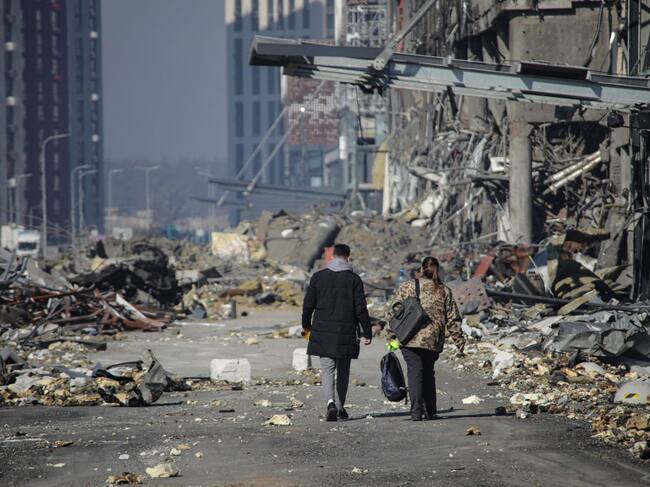 Personas caminan entre los escombros que generan los bombardeos en Kiev