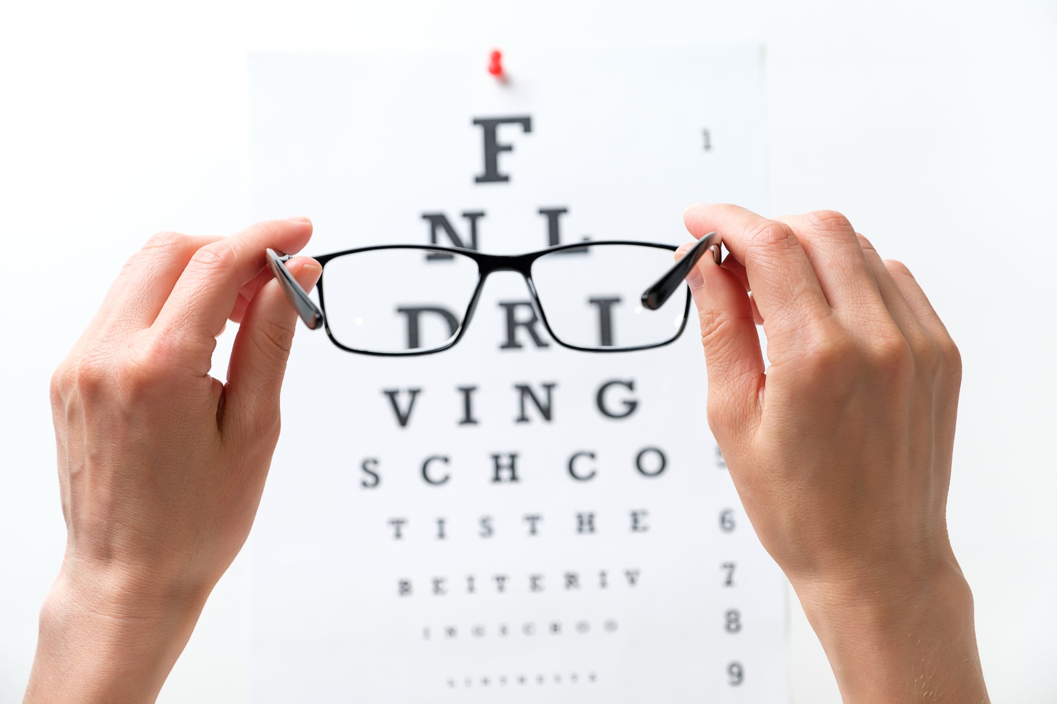 Modern fashion glasses in the hands of a woman or girl, next to the diagram of the Snellen vision test. Ophthalmology, visual acuity testing, treatment and prevention of eye diseases. The concept of poor vision, blindness, treatment of an ophthalmologist.