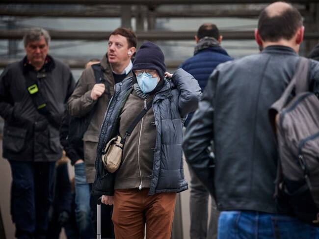 Un trabajador camina con mascarilla por la ciudad de París en Francia