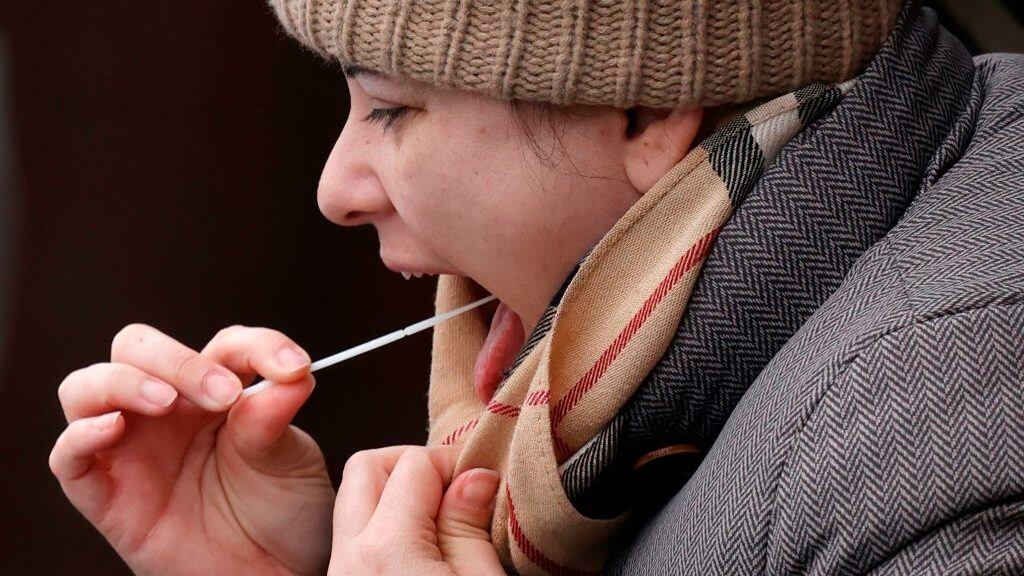 A woman swabs her throat at a coronavirus testing site set up at the Bramley Inn in the village of Bramley, west of London, on February 17, 2021 as part of surge testing to monitor and suppress the spread of the Covid-19 variant first identified in South Africa. (Photo by Adrian DENNIS / AFP) (Photo by ADRIAN DENNIS/AFP via Getty Images)